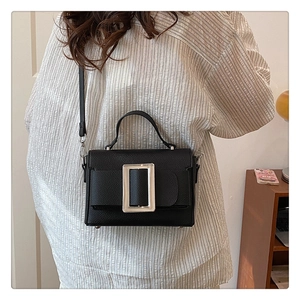 Detail of black lychee grain leather handbag with silver buckle worn by a model