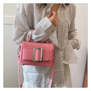 Detail of pink pebbled leather bag featuring a prominent silver square metal buckle