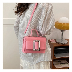 Close-up of pink lychee textured handbag with large square silver metal buckle detail