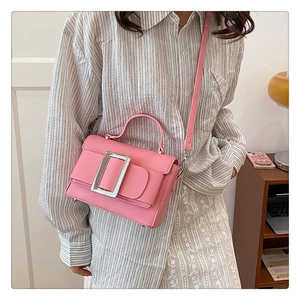 Detail of pink lychee leather handbag featuring a large silver square buckle and top handle