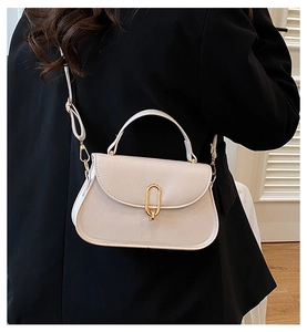 Détail du sac crème avec boucle dorée et bandoulière porté sur une veste de tailleur noire