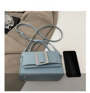 Detail of light blue litchi grain leather bag with oversized silver square buckle