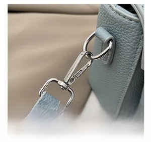 Detailed close-up of silver metal hardware hook and stitching on light blue leather bag