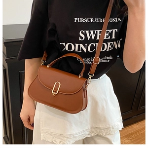 Détail d'un sac à bandoulière en cuir marron avec fermoir ovale doré et poignée