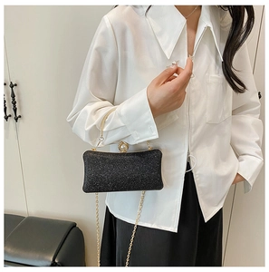 Dettaglio pochette da sera nera glitterata con cornice dorata e chiusura a perla