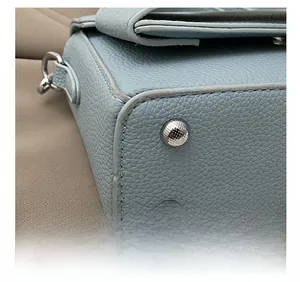 Detailed close-up of blue lychee leather handbag base with silver hardware and stitching