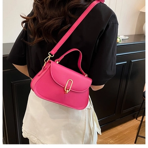 Detailed side view of a magenta crossbody bag with gold buckle on a model