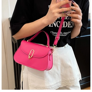 Detail of flamingo pink shoulder bag featuring a polished gold oval metal twist lock