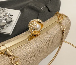 Dettaglio della pochette dorata con strass scintillanti e chiusura a sfera con perla