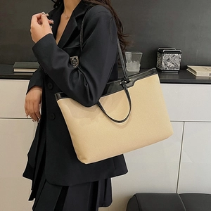 Minimalist beige canvas tote with black leather trim and handles in a stylish side view