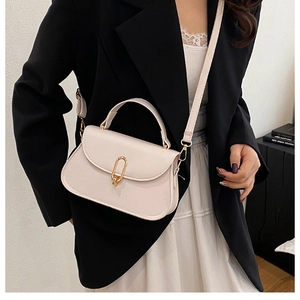 Detail of cream white leather handbag with golden U-shaped buckle on a black blazer