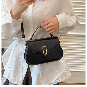 Detail of a black matte shoulder bag with a gold oval twist lock and elegant white lace sleeve