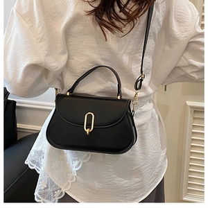 Detail shot of black leather saddle bag with gold oval lock worn by a model
