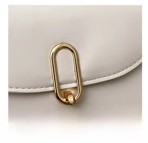 Détail du sac en cuir blanc mat avec boucle dorée et surpiqûres blanches précises