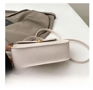 Gros plan détaillé du fond plat et du fermoir tournant en métal doré d'un sac à main blanc cassé