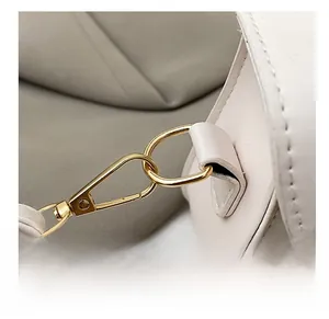 Détail du crochet en métal doré pâle et de l'anneau en D sur sac en cuir blanc