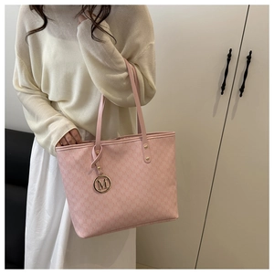 Close-up of pink tote bag with M-letter monogram pattern and gold logo pendant detail