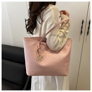 Close-up of pink tote bag featuring repeating M patterns and a gold logo pendant