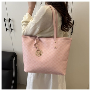 Macro detail of pink monogram tote bag featuring golden M-letter charm and dual straps