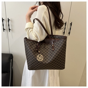 Close-up of monogram pattern tote bag with golden M charm and spacious interior