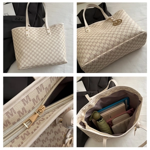 Detail view of large cream tote bag with brown M patterns and golden zipper closure