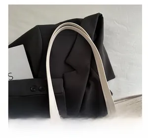 Detail of white leather handle with knot design and gold rivets on monogram tote bag