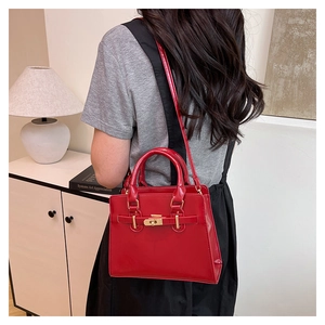 Glossy red handbag with gold hardware shown in a stylish home setting