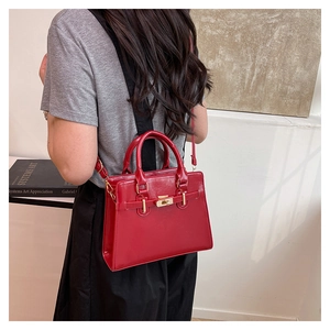 Classic red rectangular handbag with gold hardware shown on a shoulder for scale
