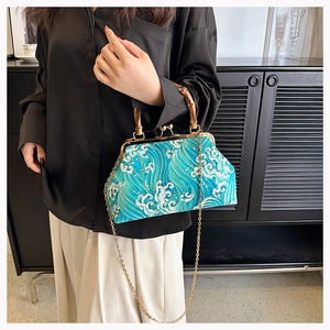 Detail of vintage frame bag with blue wave pattern, bamboo handle, and gold metal clasp