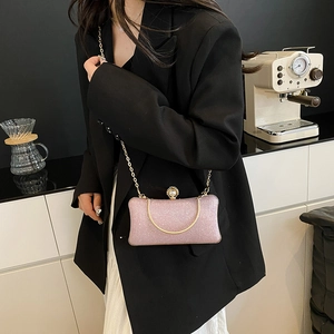Borsa da sera rosa con paillettes, catena dorata e chiusura a perla su outfit elegante