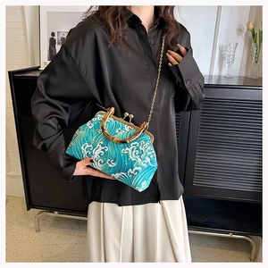 Close-up of retro wave print bag with bamboo handle and gold chain on elegant model
