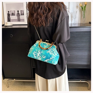 Detail of blue wave pattern handbag with bamboo handle and chain strap on model