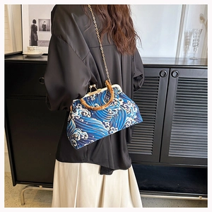 Retro wave pattern bag with bamboo handle and gold chain worn by a model in profile