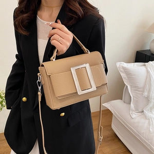 Chic beige drawstring satchel with silver square buckle shown on a model in a home setting