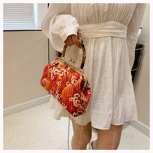 Detail of red wave pattern handbag with bamboo handle and golden metal clasp closure