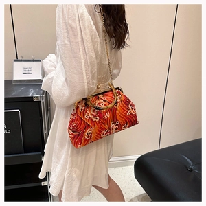 Model showing a vintage style handbag with bamboo handle and red wave patterns