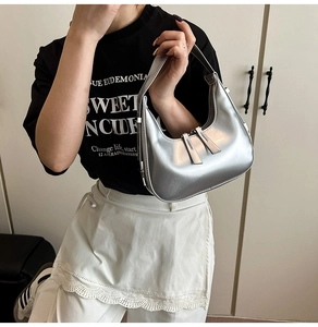 Détail d'un sac hobo croissant argenté avec double fermeture éclair et finition brillante
