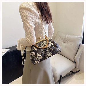 Detailed view of bamboo handle and ukiyo-e wave pattern on a retro crossbody bag