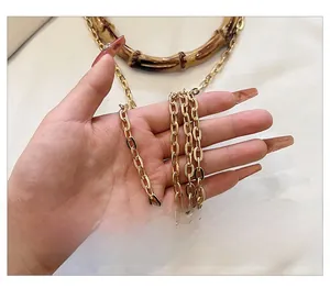 Close-up of golden metal chain strap and retro bamboo handle detail of a handbag