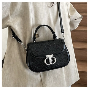 Dettaglio della borsa a sella nera goffrata con fibbia in argento su modella elegante
