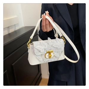Detailed close-up of white lace butterfly embroidery on a stylish crossbody bag