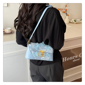 Detail of light blue crossbody bag featuring 3D butterfly embroidery and gold twist lock