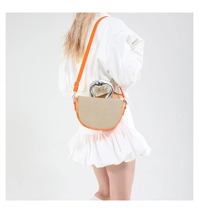 Detailed back view of orange and beige woven bag with silver metal handle on model