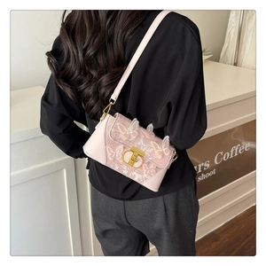 Detail of pink crossbody bag with 3D butterfly embroidery and gold T-lock on a model