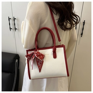 Detail view of red and white snakeskin pattern crossbody bag with a heart print silk scarf