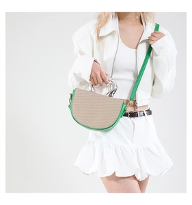Detail of green leather piping and natural woven texture on saddle bag with silver metal handle