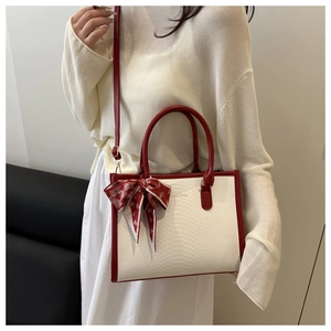 Détail du sac à main blanc motif crocodile avec anses rouges et foulard à pois élégant