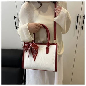 Detail view of white snake-textured tote with red leather trim and silk scarf handle