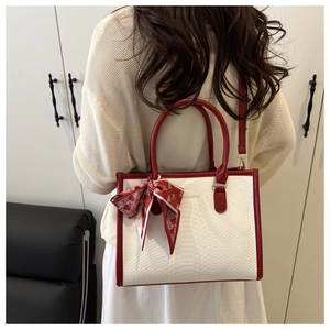 Detail of elegant white faux snake skin texture handbag with red handles and silk scarf