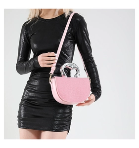 Pink semi-circular bag with unique silver metal handle shown on fashion model